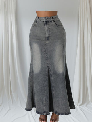 Model wearing a high-waisted gray denim maxi skirt with a dramatic flare hem and front seam detail.