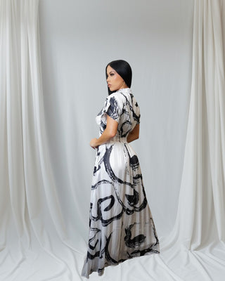 Woman wearing a black-and-white abstract print button-down collared maxi dress with pockets — elegant flowy silhouette from Tulley’s Boutique.