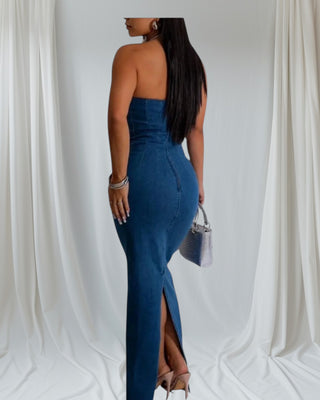 Woman wearing strapless blue denim maxi dress with fitted silhouette, back slit, and silver accessories — Tulley’s Boutique.