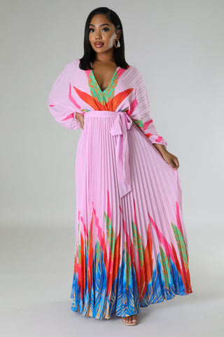 Woman wearing Tropical Grace Pleated Maxi Dress in pink with vibrant tropical print — flowy pleated skirt and tie waist.