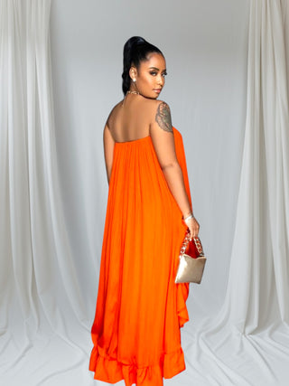 Woman wearing a bold orange strapless high-low ruffle dress with a flowing hem — elegant summer fashion from Tulley’s Boutique.