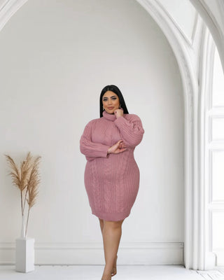 Model wearing a cozy pink knitted sweater dress with a turtleneck, showcasing a stylish cable knit design.