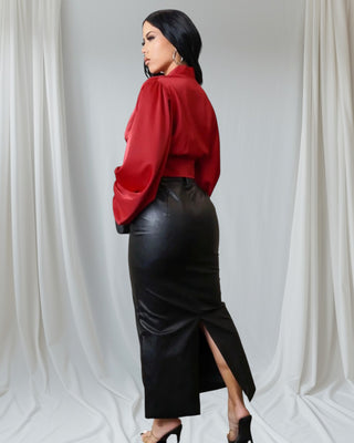 Model wearing black faux leather midi pencil skirt with high waist and clear heels, styled with red blouse and clutch.