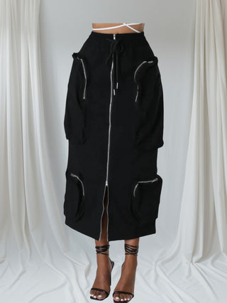 Woman wearing a black high-waisted utility midi skirt with silver zipper details and a front slit — Urban Utility Cargo Skirt from Tulley’s Boutique.