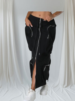 Woman wearing a black high-waisted utility midi skirt with silver zipper details and a front slit — Urban Utility Cargo Skirt from Tulley’s Boutique.