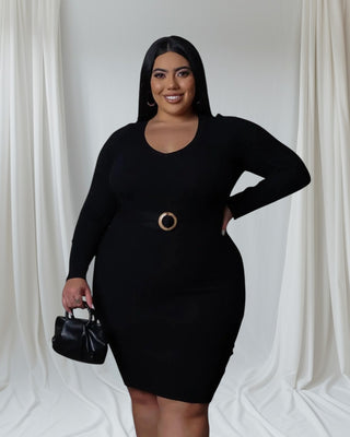 Model wearing Fine & Fluffy Sweater Dress in black with belted waist detail, holding small handbag.