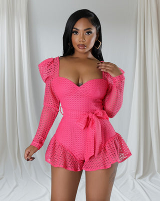 Woman wearing vibrant hot pink mesh long-sleeve romper with sweetheart neckline, open back, and ruffle hem — Tulley’s Boutique