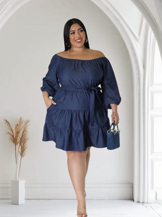 Plus-size woman wearing off-the-shoulder blue denim summer dress with self-tie waist and pockets — Tulley’s Boutique