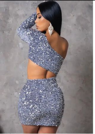 model wearing one-shoulder silver sequin mini dress with waist cut-out.