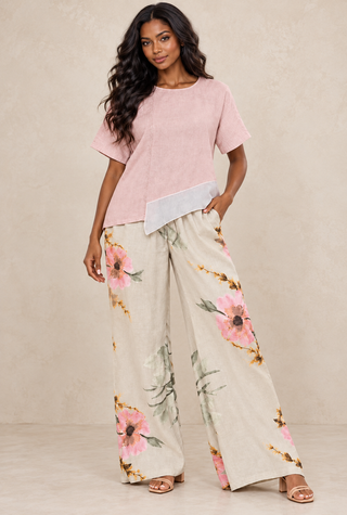 Woman wearing a blush pink linen asymmetrical top with floral wide-leg linen pants – Tulleys Boutique