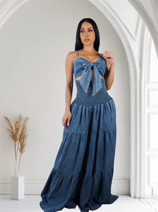 Woman wearing a denim  jumpsuit with a smocked waist and adjustable straps,  tie in front