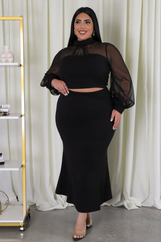 Model wearing plus-size black mesh two-piece skirt set with sheer sleeves and mock neckline