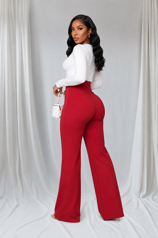 Woman wearing red high-waisted wide-leg Power Move Pants with tailored front seams and a fitted white long-sleeve top.