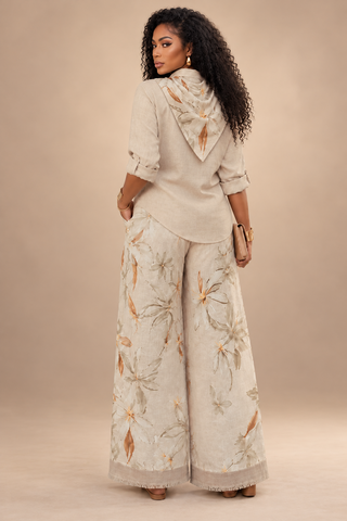 Back view of the cream linen pants set showing the floral scarf draped in back, curved shirt hem and wide-leg floral pants