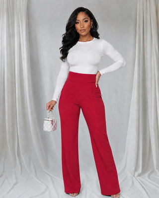 Woman wearing red high-waisted wide-leg Power Move Pants with tailored front seams and a fitted white long-sleeve top.