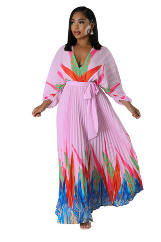 Woman wearing Tropical Grace Pleated Maxi Dress in pink with vibrant tropical print — flowy pleated skirt and tie waist.