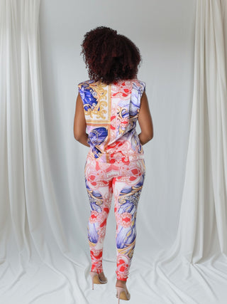  model wearing a colorful patterned two-piece outfit featuring a sleeveless top and fitted leggings in vibrant hues of red, blue, and gold.