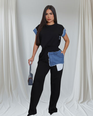Woman wearing a black outfit with denim accents in the sleeve and the pockets 