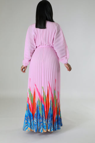 Woman wearing Tropical Grace Pleated Maxi Dress in pink with vibrant tropical print — flowy pleated skirt and tie waist.