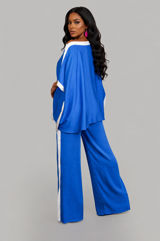 Woman wearing a royal blue two-piece pant set with oversized flowy top, white contrast trim, and wide-leg pants.