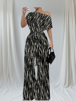 Person wearing a black and white tie-dye off-shoulder wide leg jumpsuit with Tie waist for flattering figure