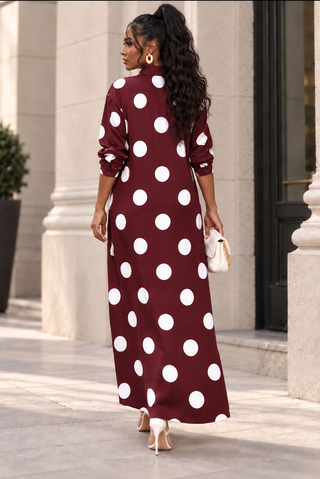 Back view of a burgundy polka dot maxi shirt dress styled with a white quilted handbag and gold hoop earrings