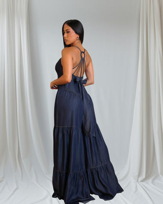 Navy blue tiered jumpsuit with distinctive strappy back design featuring circular detail. Elegant silhouette shown from behind.