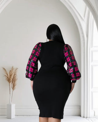 "Plus size model wearing a black bodycon dress with bold pink plaid sequined statement sleeves, striking a confident pose 