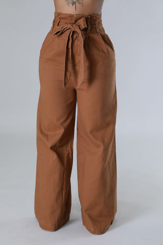 Front close-up of brown high-waisted wide-leg denim pants with paperbag waist and self-tie bow belt