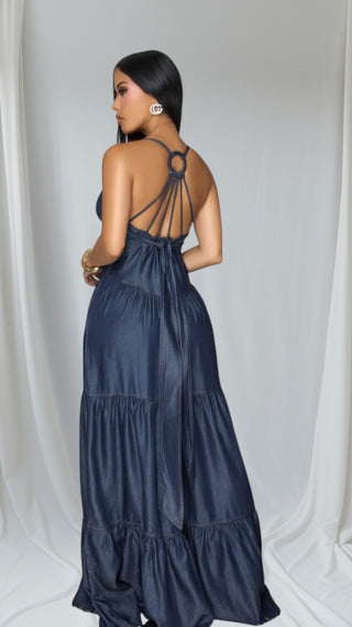 Navy blue tiered jumpsuit with distinctive strappy back design featuring circular detail. Elegant silhouette shown from behind