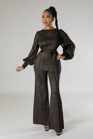 Model wearing black metallic two-piece pant set with tie-waist blouse and wide-leg pants