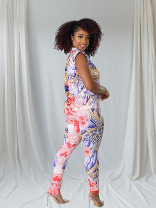  model wearing a colorful patterned two-piece outfit featuring a sleeveless top and fitted leggings in vibrant hues of red, blue, and gold.