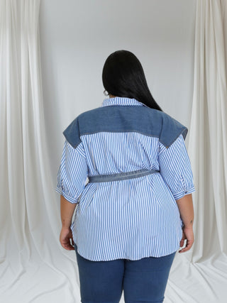 Back view of a model wearing a stylish blue and white striped oversized shirt with denim accents, showcasing a tied waist detail.