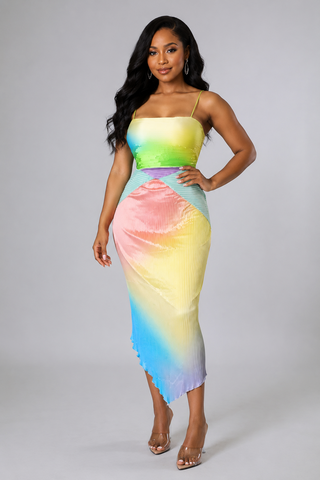 Model wearing the Sunset Sorbet multicolor pleated asymmetrical midi dress with spaghetti straps and a pastel rainbow design