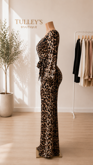 Women’s leopard sequin wrap jumpsuit with long sleeves, faux wrap neckline, waist tie, and wide-leg pants displayed on a boutique mannequin.
