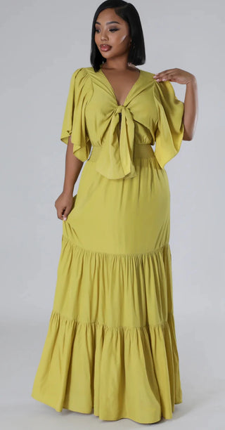 Woman wearing blush pink tiered maxi dress with ruched waist and flutter sleeves