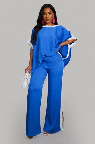 Woman wearing a royal blue two-piece pant set with oversized flowy top, white contrast trim, and wide-leg pants.