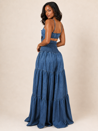 Back view of blue acid wash denim jumpsuit with elastic back and smocked waist
