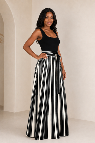     Model wearing the Bold Direction black sleeveless maxi dress with a cream striped full skirt and self-tie waist, front view.