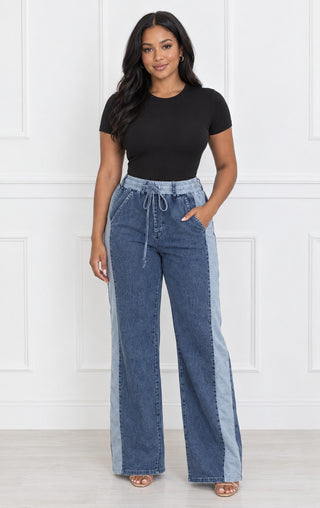 Model wearing high-waisted wide-leg denim stripe drawstring pants with a light-wash side panel stripe and elastic waistband, styled with a black bodysuit, front view