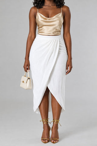 Close-up of the ivory wrap midi skirt showing the high waistband, ruched hip and curved high-low front slit