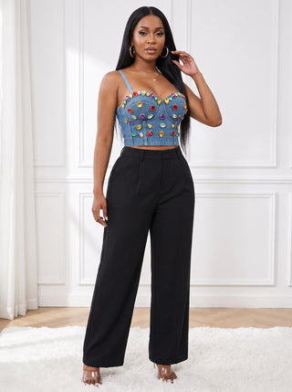 Three-quarter view of model in The Jewel Drip gem-embellished denim corset crop top with black wide-leg trousers and clear strappy heels