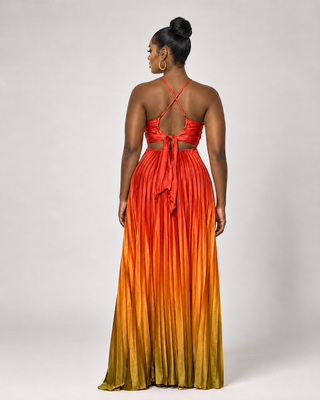 Back view of the orange-to-gold ombre pleated maxi dress showing crisscross straps, open back cutout and tie detail