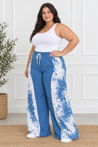 Side view of plus size blue and white paint-splash wide-leg pants worn with a white tank top