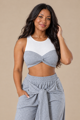 Close-up of the white ribbed upper and gray twist-knot bust of the crop top with the elastic waistband and knotted tie sleeves on the joggers