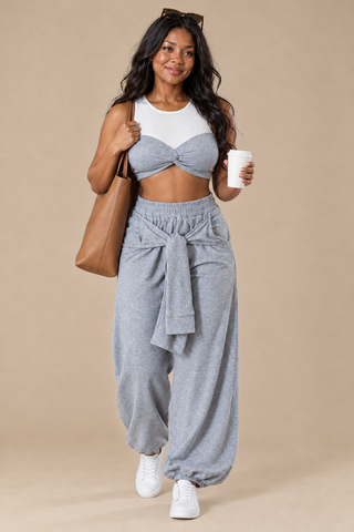 Travel day look in the heather gray two-piece jogger set with white sneakers, a tan tote, sunglasses and a coffee