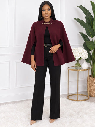 Model wearing the Royal Rein burgundy stand-collar cape with gold hardware at the neck, open front over a black top and black trousers, front view