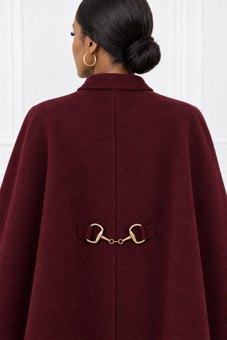 Close-up of the burgundy cape's back with gold double-ring link hardware on fabric tabs and center back seam
