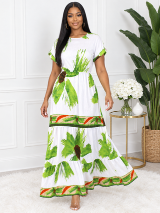 Model walking in white tropical leaf print maxi dress showing tiered skirt movement