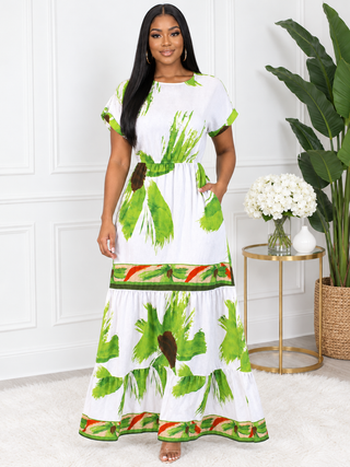 Model in white and green tropical leaf print tiered maxi dress with short sleeves, hand in side pocket